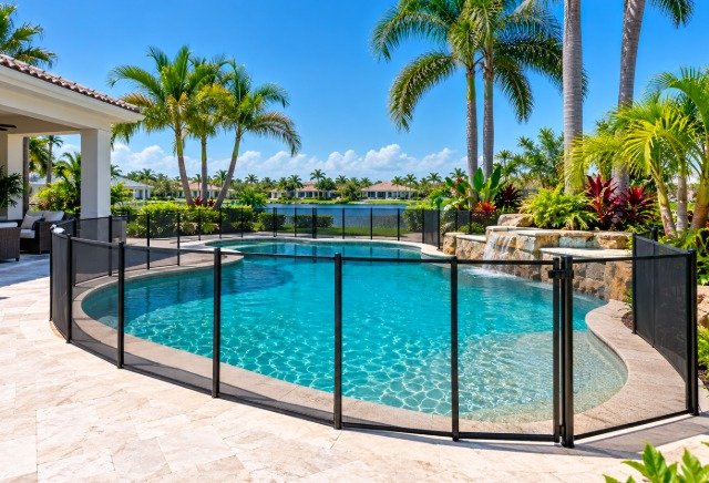 Removable mesh pool fence with a self-closing gate around a resort-style pool