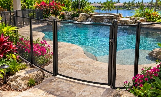 Mesh pool fence gate on a freeform pool surrounded by tropical flowers